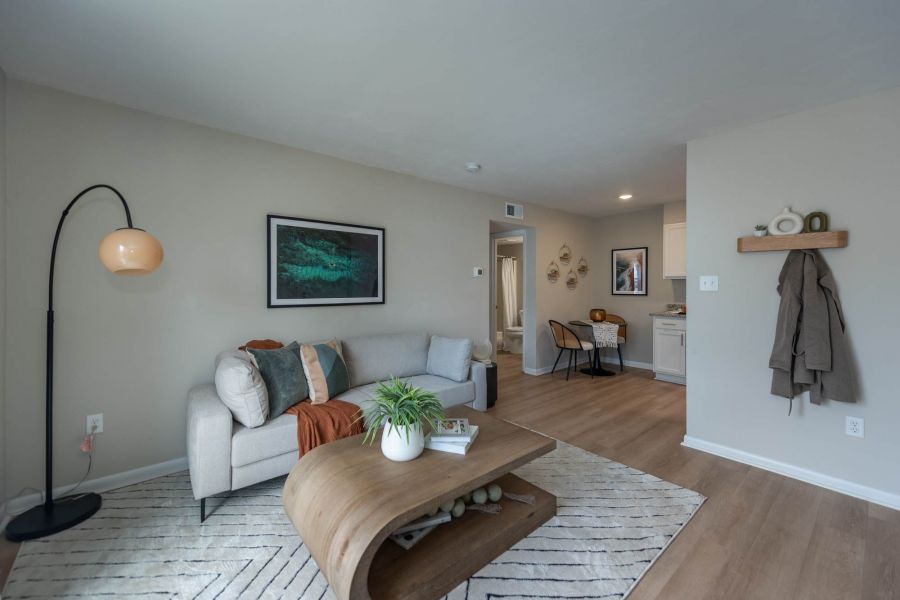 Attain at Chic's Beach apartment homes with Modern living room with neutral tones, a gray sofa, wooden coffee table, and artwork on the wall.