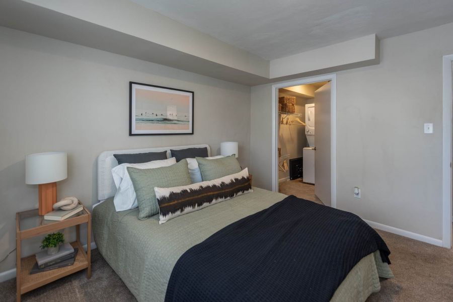 Attain at Chic's Beach homes with A neatly made bed in a cozy bedroom with neutral walls and a small open closet in the background.