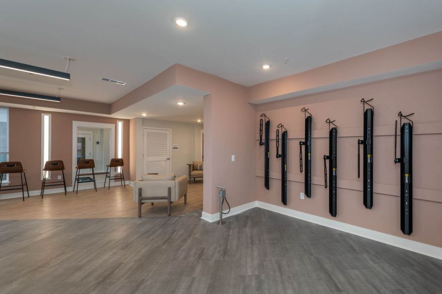 Attain at Chic's Beach homes with Modern exercise room with wall-mounted fitness equipment and barstools along windows; neutral color scheme.