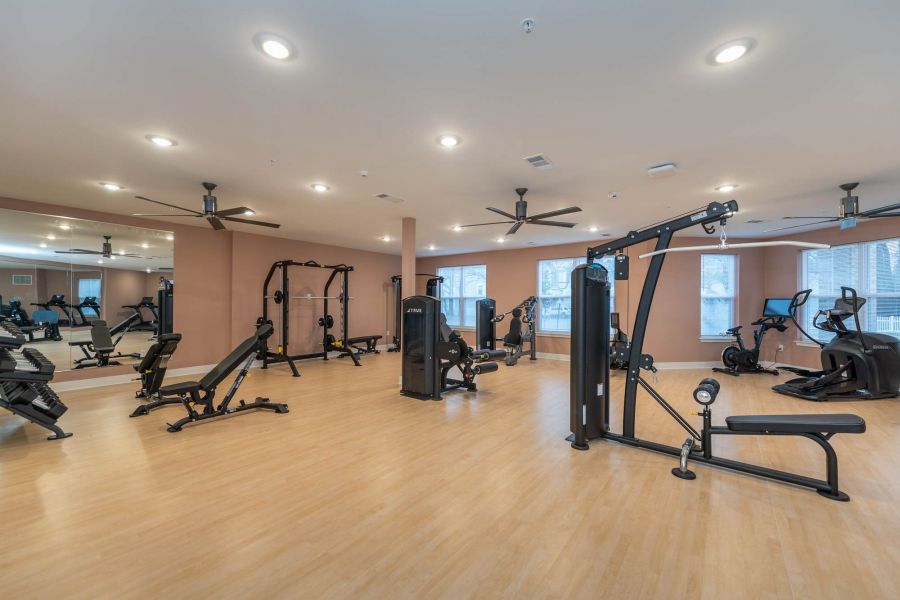 Attain at Chic's Beach homes with Spacious gym with exercise machines, weights, mirrors, and large windows on light wooden floors.