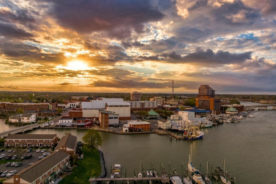 Attain at Chic's Beach homes with Aerial view of a marina and city buildings at sunset under a dramatic, cloudy sky.