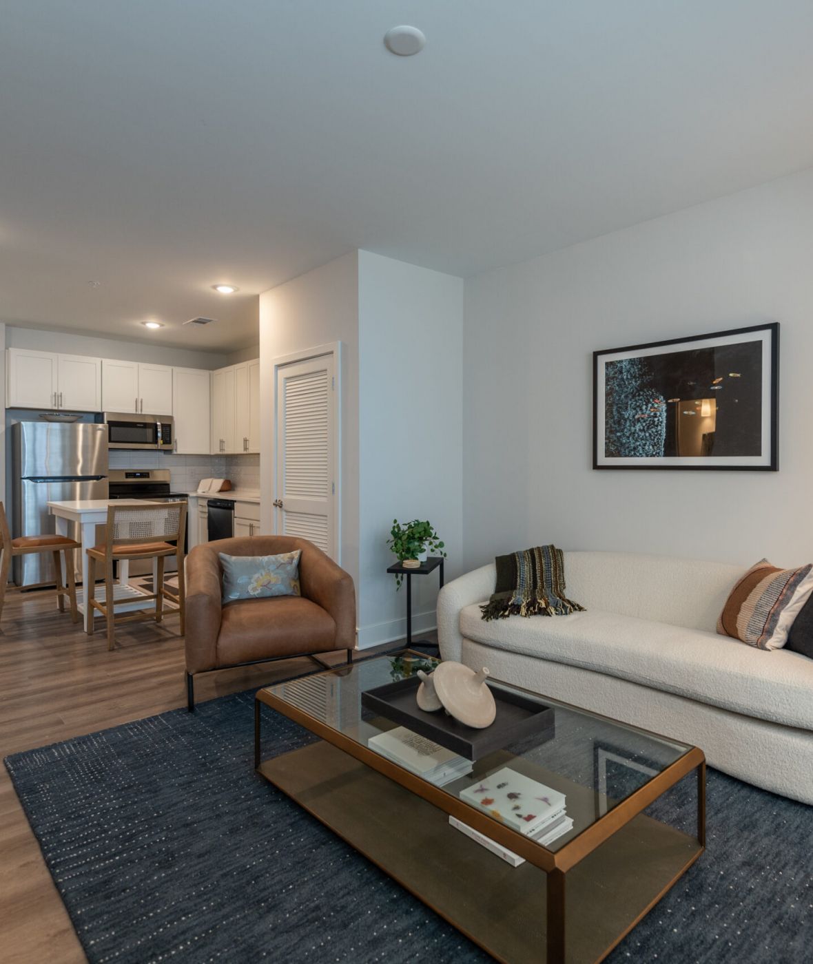 Attain on 5th apartment homes with Modern living room with a sofa, armchair, coffee table, and open kitchen in a bright apartment.