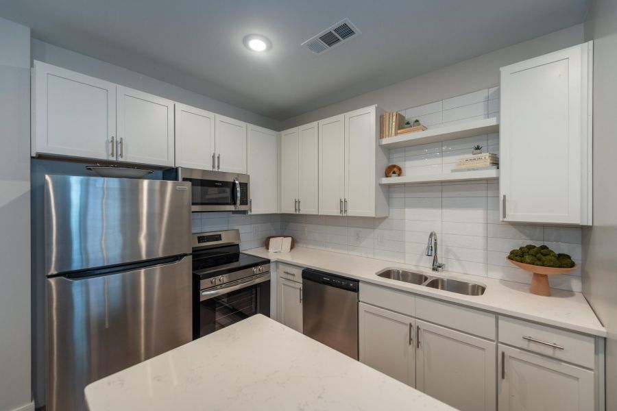 Attain on 5th apartment homes with Modern kitchen with white cabinets, stainless steel appliances, and a white countertop island.