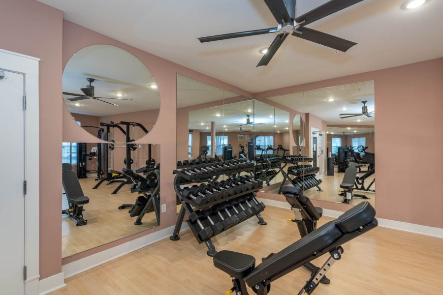 Attain at Chic's Beach homes with Modern gym room with weights, benches, large mirrors, ceiling fans, and exercise equipment.
