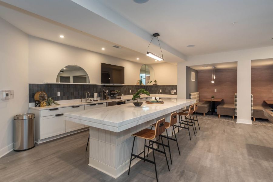 Attain at Chic's Beach homes with Modern kitchen with a large marble island, four barstools, and sleek appliances under soft lighting.