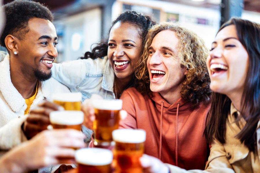 Attain on 5th apartment homes with Four friends laughing and toasting with glasses of beer at a bar or pub.