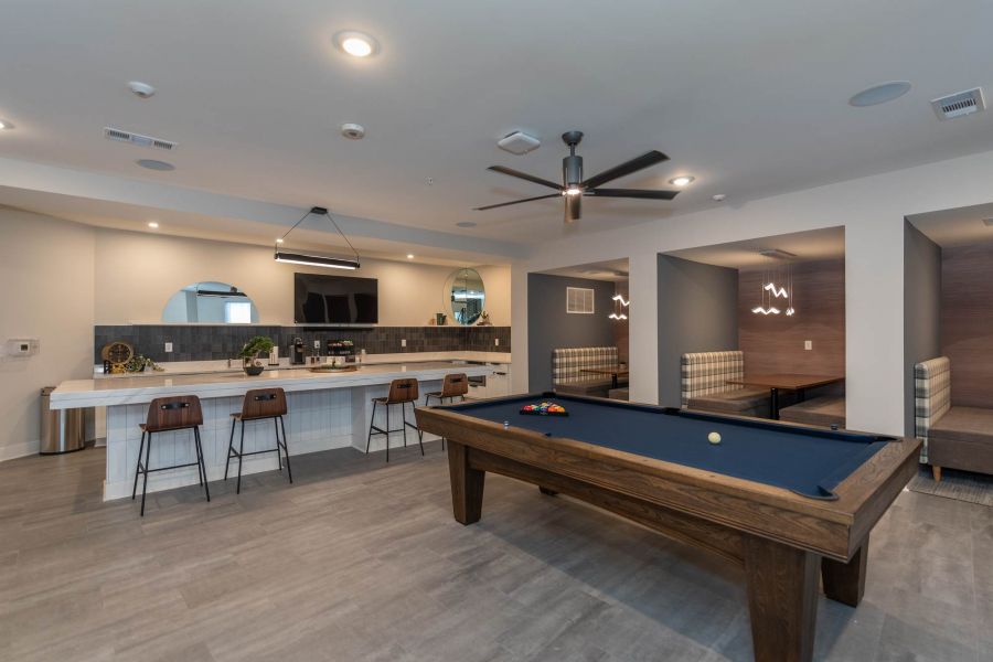 Attain at Chic's Beach homes with Modern lounge with a pool table, bar seating, and cozy booth areas under soft lighting and neutral decor.